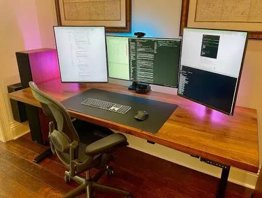 My desk setup: three monitors on a standing desk